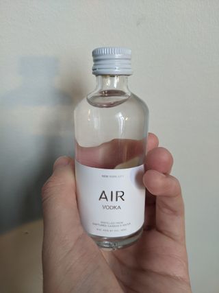 a hand holding a small bottle of clear liquid