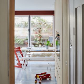 view from a hallway into a family kitchen diner with a dining table, Tripp Trapp high chair, toy car and bifold doors