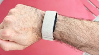Close-up of the Garmin Cirqa on a user's wrist against a red background