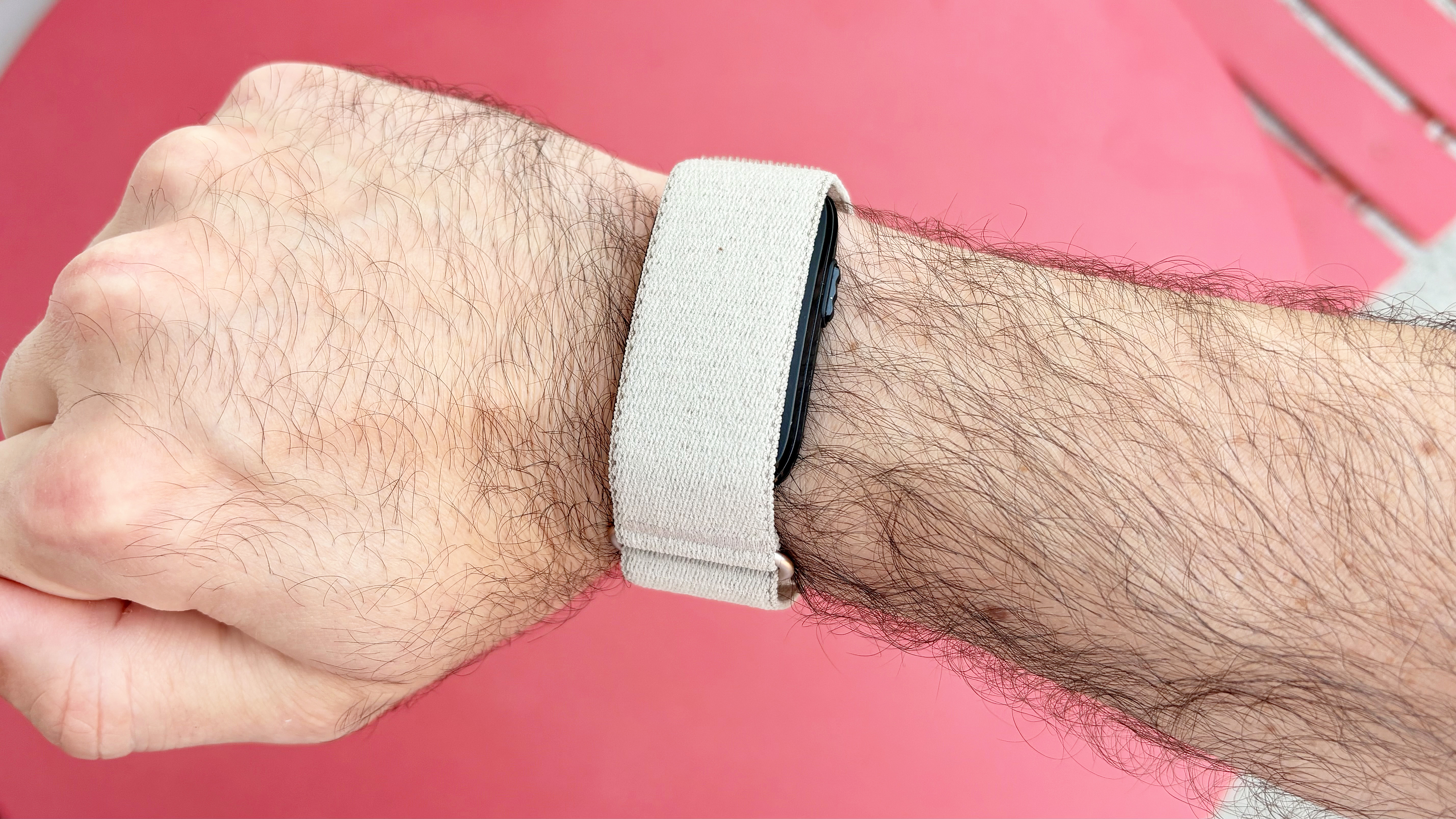 Close-up of the Garmin Cirqa on a user's wrist against a red background