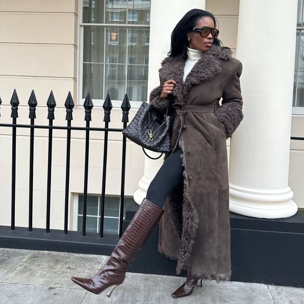 @nlmarilyn wearing a brown fur coat, black leggings and brown knee-high boots
