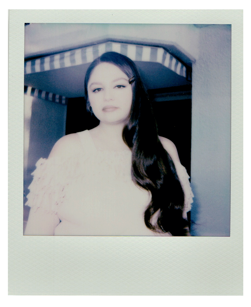 a gif of polaroids of actress Meg Stalter smiling and holding a straight face wearing an off the shoulder sweater with her hair over one shoulder