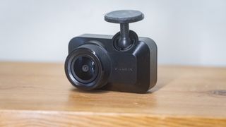 Garmin Mini 3 dashcam on a wooden table in front of a white wall