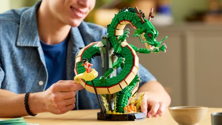 A man smiles while moving the Lego Shenron & Goku set