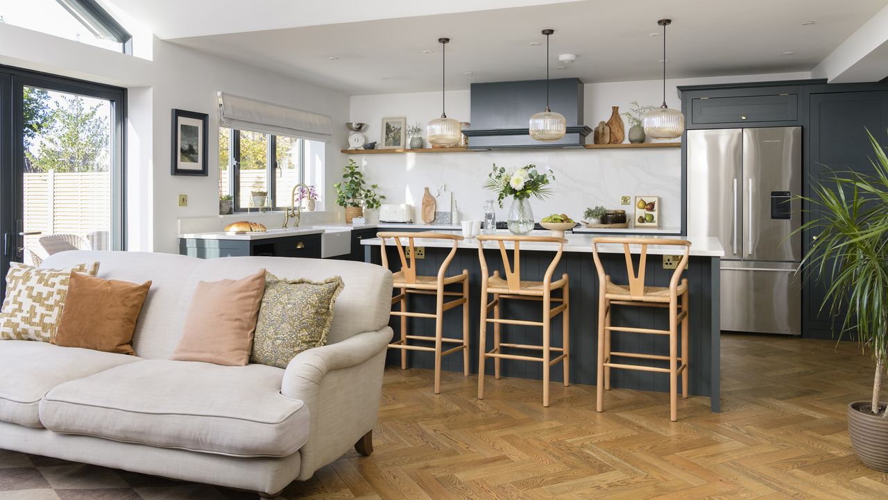 Open plan kitchen with herringbone floor and navy cabinets