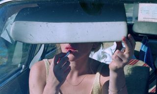 A woman applies lipstick in a car mirror in 'The Vanishing'