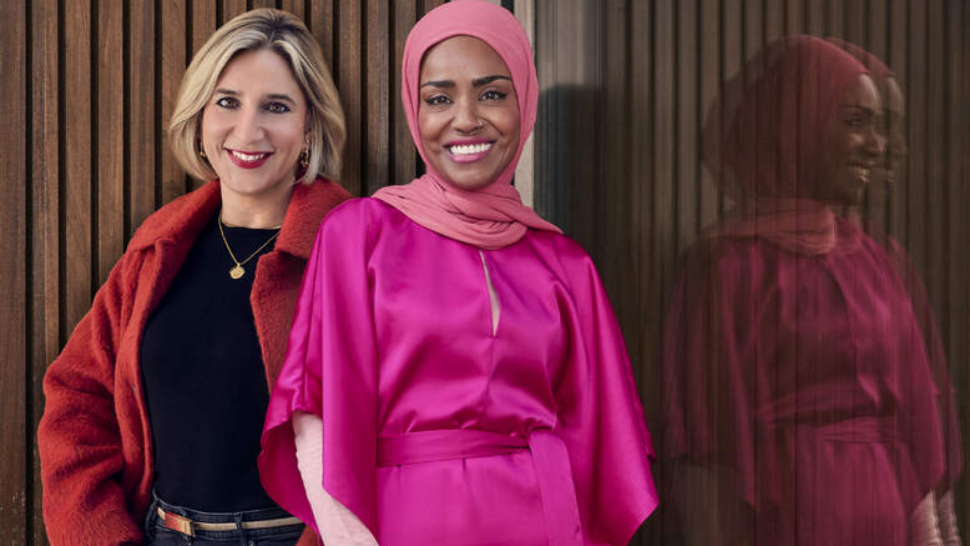 Hannah Fernando and Nadiya Hussain standing against a glass screen with Nadiya's reflection -both smiling at the camera