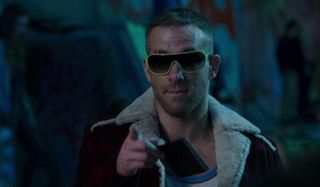 Deadpool Ryan Reynolds wearing sunglasses at night, pointing casually towards the camera