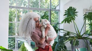 a woman with long grey hair holds a fluffy white cat