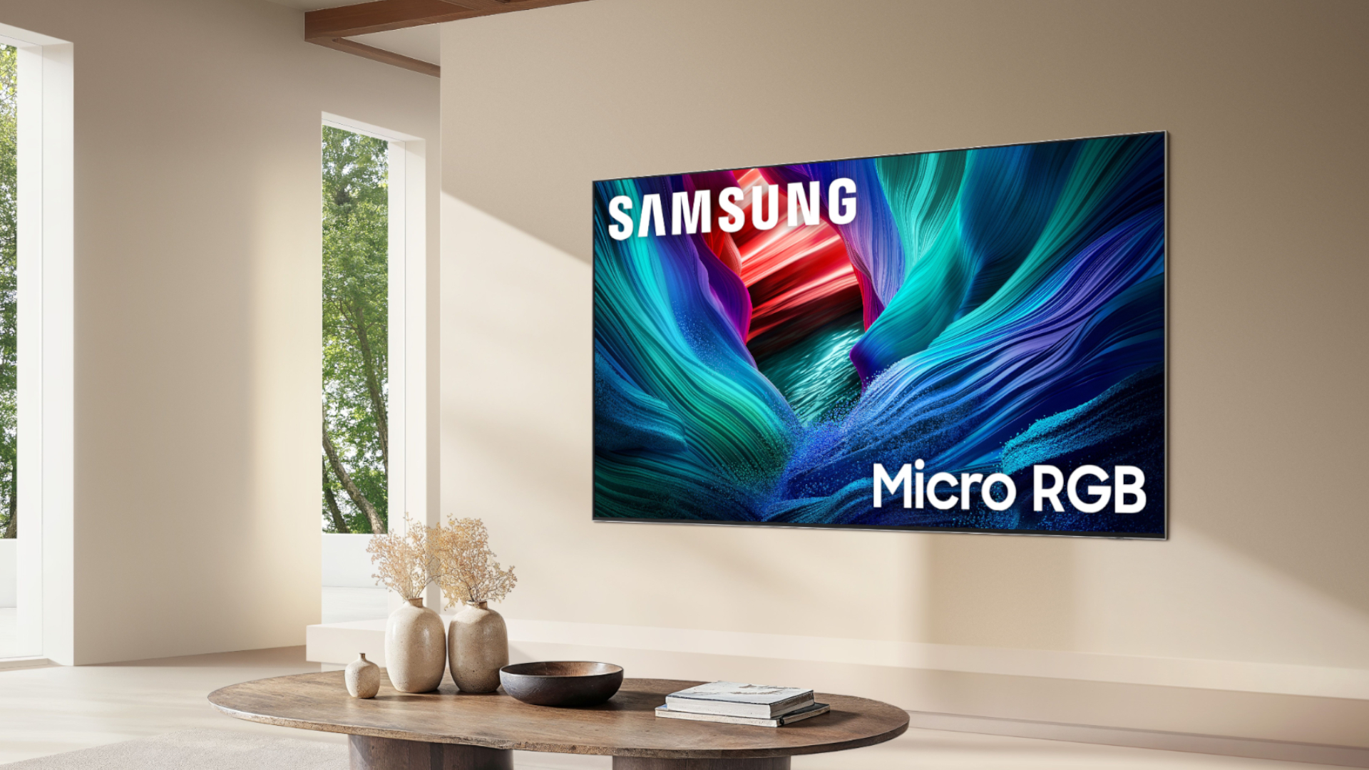 The 115-inch Samsung Micro RGB TV mounted on the wall of a modern, beige-colored living room. On the screen is an abstract, multicolored image alongside the following words: "Samsung Micro RGB."