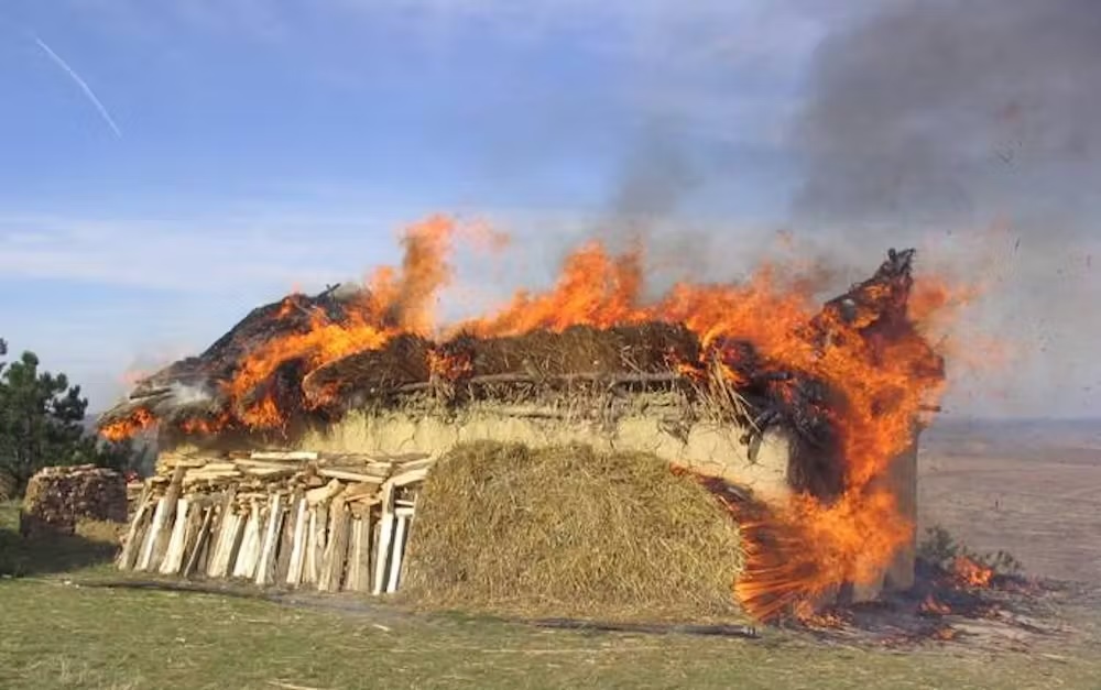 A photograph of a primitive house on fire