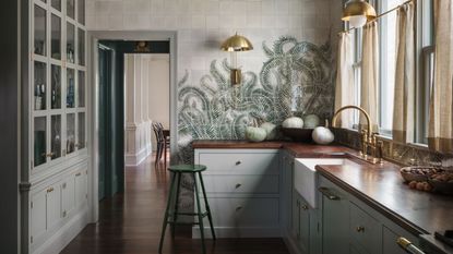 grey green shaker kitchen with dark wooden worktops and green fern printed tile murals