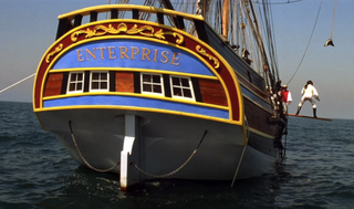 A classic sailing ship named Enterprise painted in red, gold, and blue