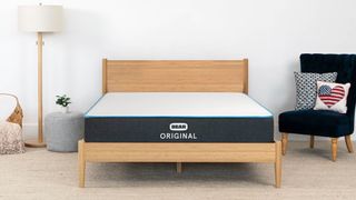 Best mattress in a box: Bear Original Mattress placed on a wooden bedframe next to a black highback chair