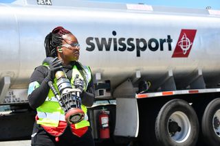 Swissport refuelling worker stood in front of a fuel tanker emblazoned with the company logo