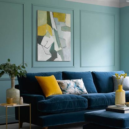 Blue living room with wall panelling and blue velvet sofa