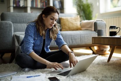 Woman sitting on floor at home working on latop