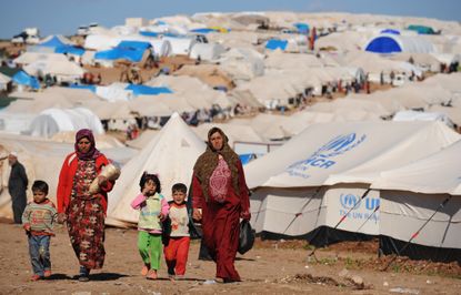 Syrian refugees walk through a camp.