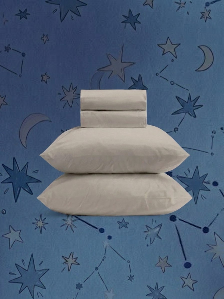 Coop Sleep Goods Cotton Percale sheet set in a neat pile against a blue background of stars, edited by Gemini