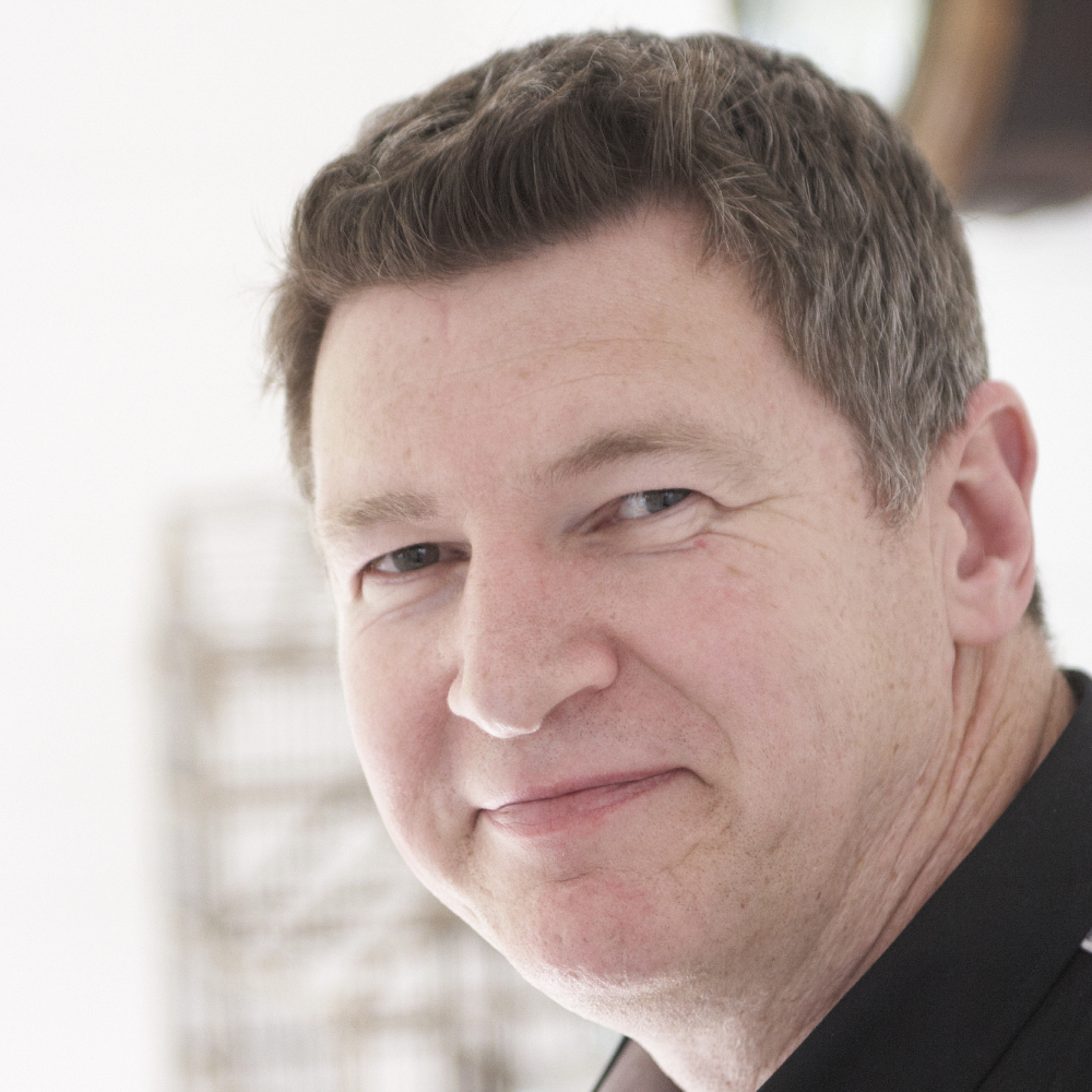 male with short brown hair smiling side on to camera