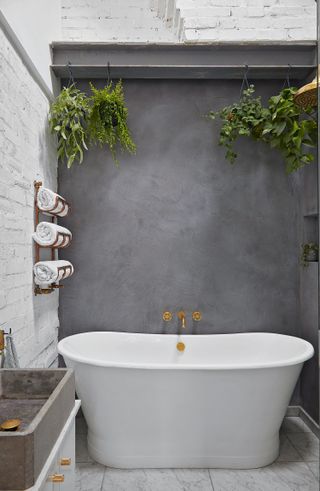 A rustic bathroom with concrete walls and a white, shapely tub