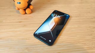 A black Infinix GT 30 Pro phone on a wooden desk