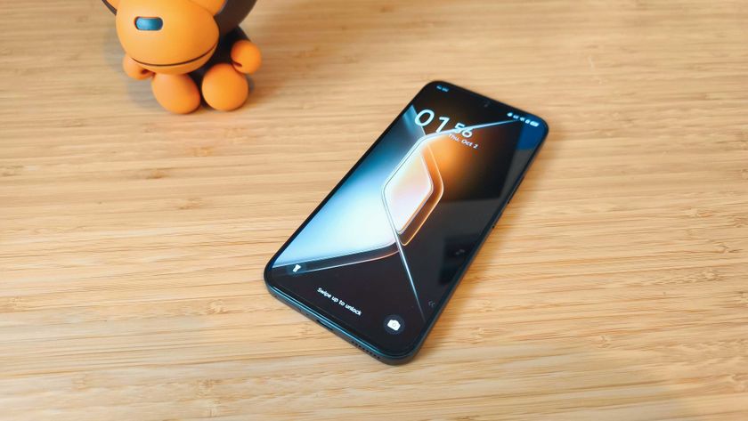 A black Infinix GT 30 Pro phone on a wooden desk