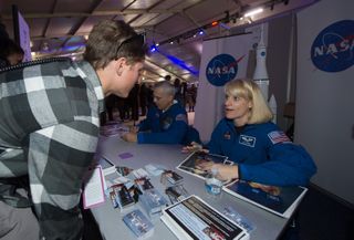 NASA Astronaut Kate Rubins signs autographs at the NASA booth set up on the National Mall as part of the National Day of Service, on Jan. 19, 2013, in Washington.