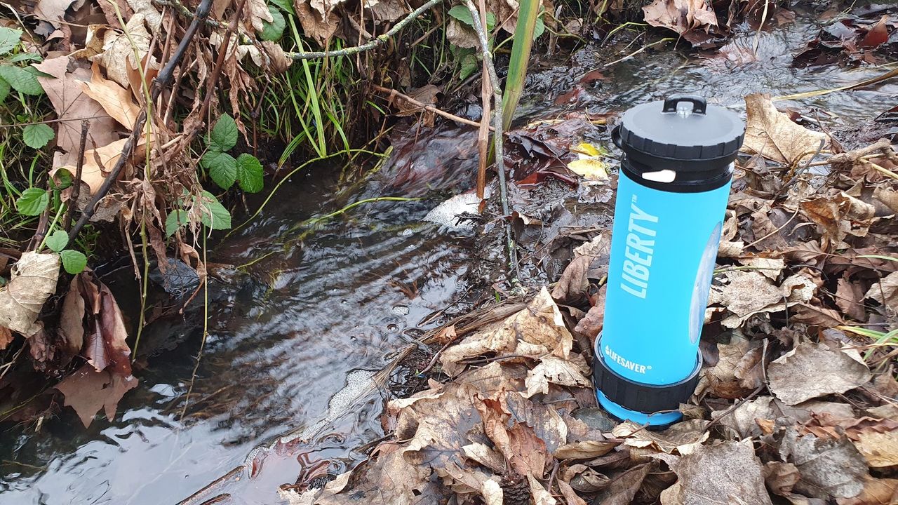 Lifesaver Liberty water bottle next to a muddy stream