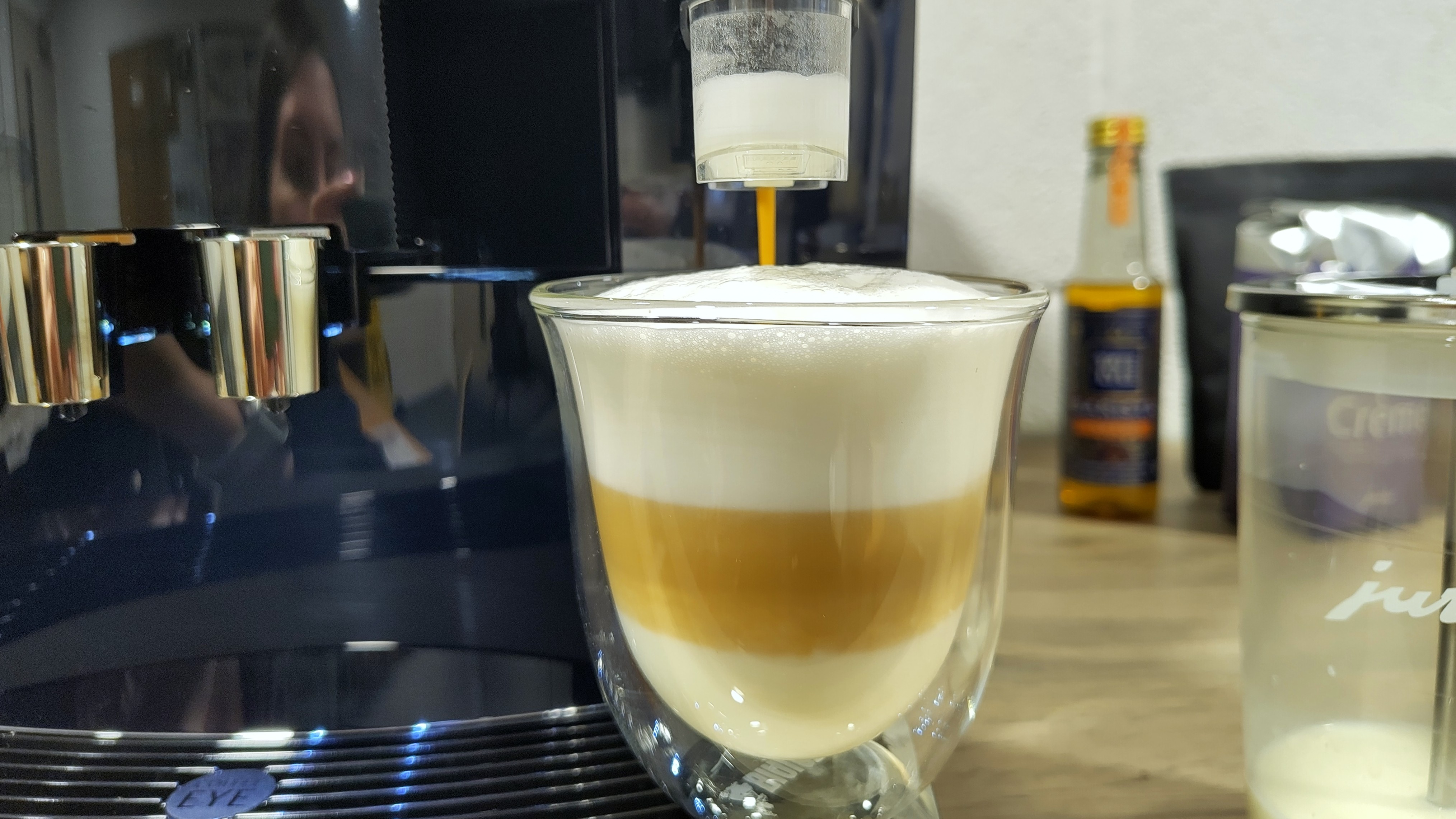 Jura J10 coffee maker preparing a latte macchiato with syrup