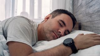 Happy man sleeping wearing sports watch