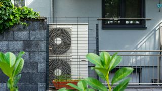 Air source heat pump in a residential garden with cage around it