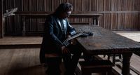 Tony Iommi sits at an old table and contemplates his guitar.