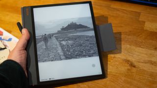 BOOX Note 3 tablet in hand over wooden table