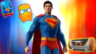 Superman poses besides an orange and white crate, and two small mascots