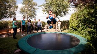 Woman jumping on trampoline in back garden