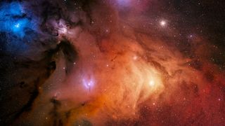 A colorful portrait of the Rho Ophiuchi stellar nursery comprised of swirling gas clouds and dense, dark filaments. The globular star cluster M4 is located at the top right of the image, while the bright star Antares can be found almost directly below.