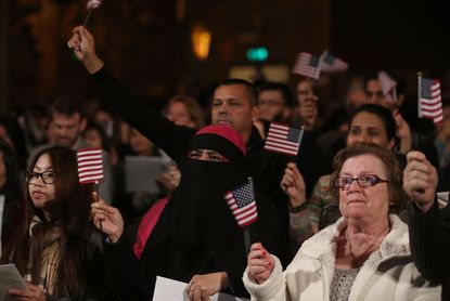 Immigrants wave American flags.