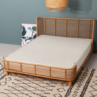 The Little Green Sheep Natural Dual Sided pocket sprung mattress on a rattan bed in a modern bedroom