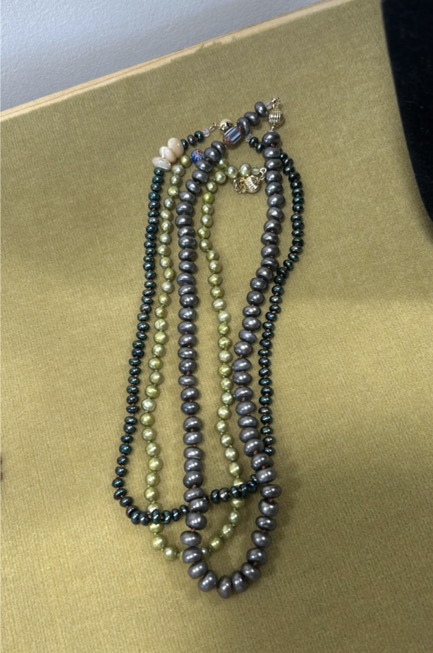strands of black and green pearls on green background
