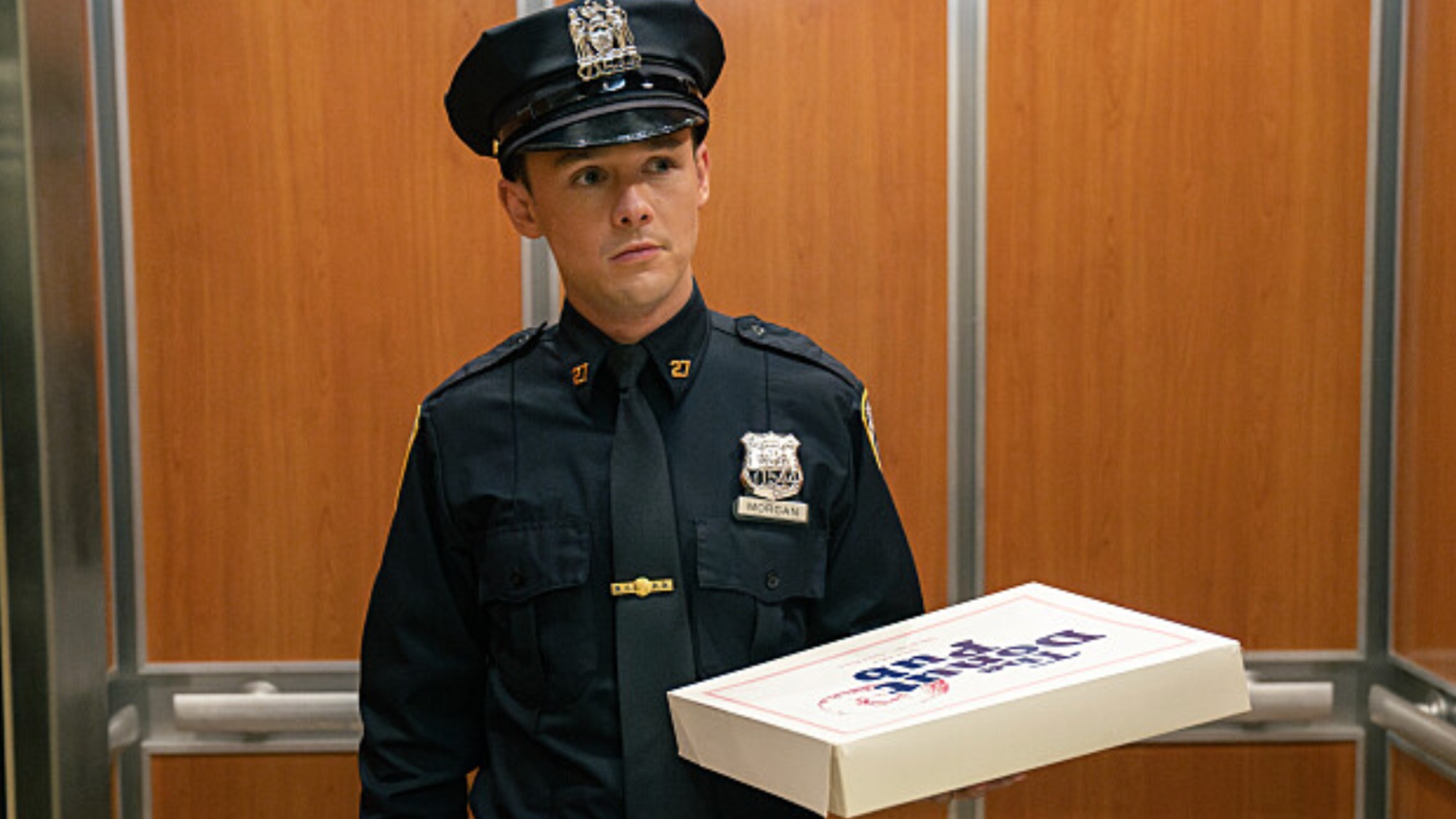 Harrison shows up to work with donuts for his coworkers on the police force. He's dressed in a blue cop uniform. 