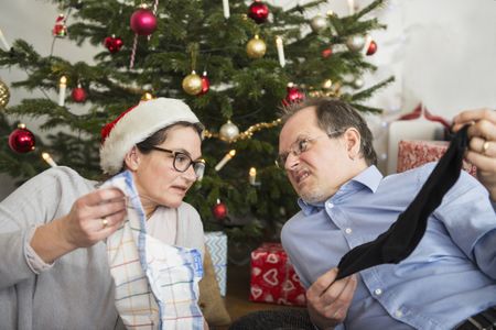 Couple beside Christmas tree with unwanted gifts