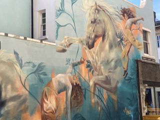 A mural on the side of a listed building of a woman and a horse