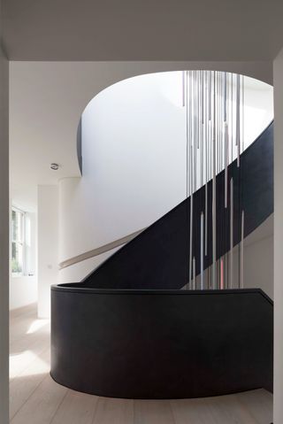 black modern curved staircase with slim pendant lights
