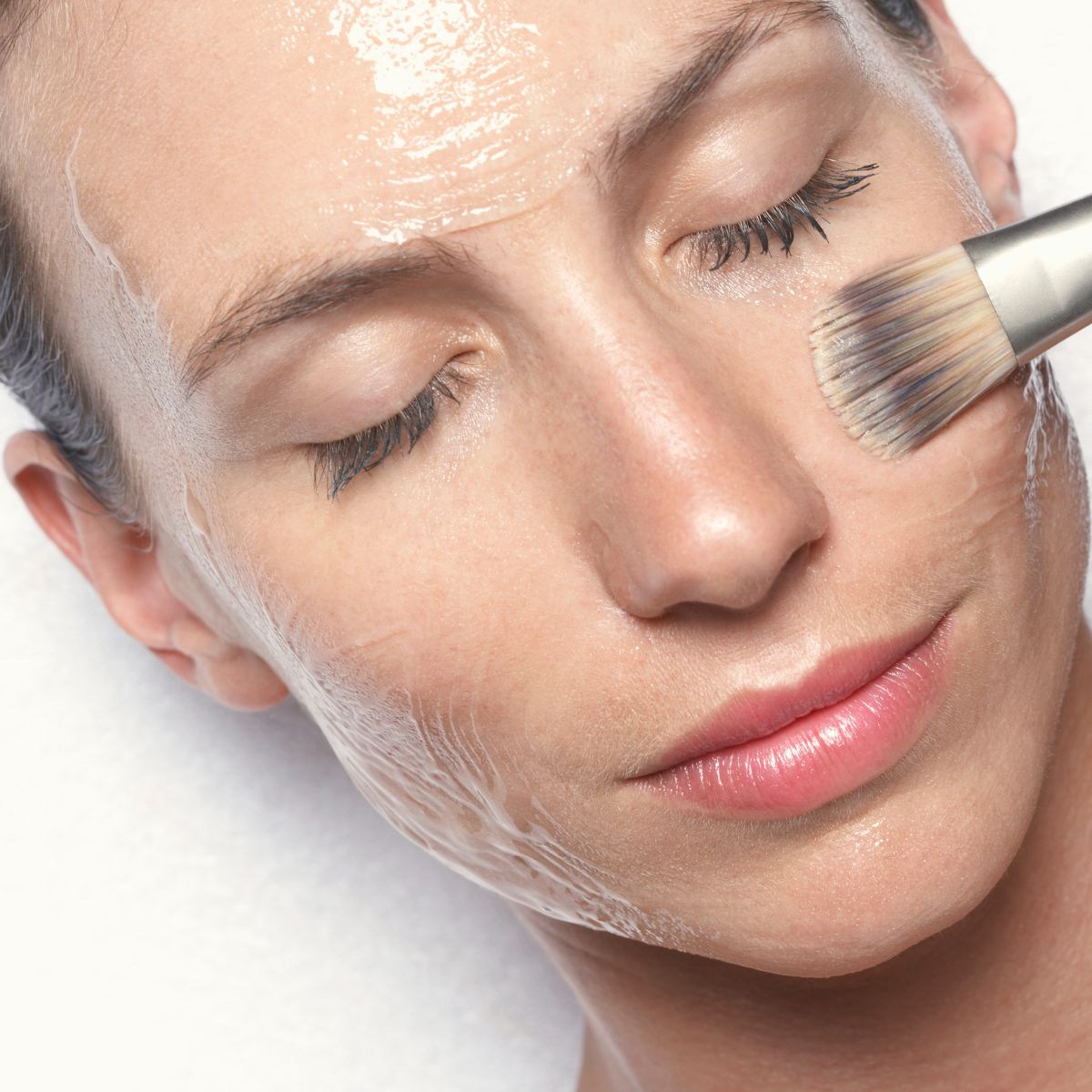 woman applying face mask with brush