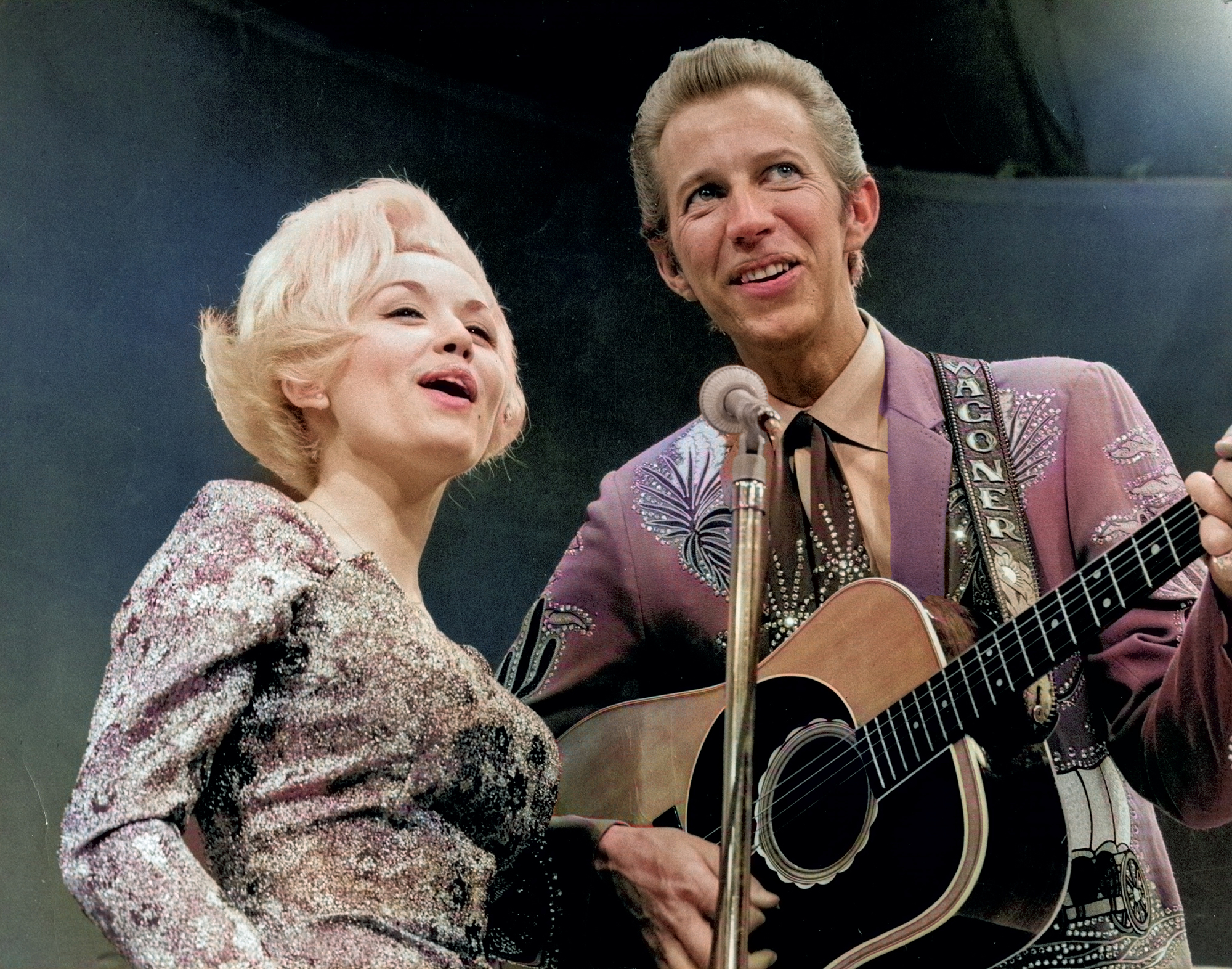 Country singer Dolly Parton and her collaborator Porter Wagoner perform onstage in circa 1967. Mr. Wagoner is wearing a Nudie Suit designed by Nudie Cohn of Nudie&#039;s Rodeo Tailors.