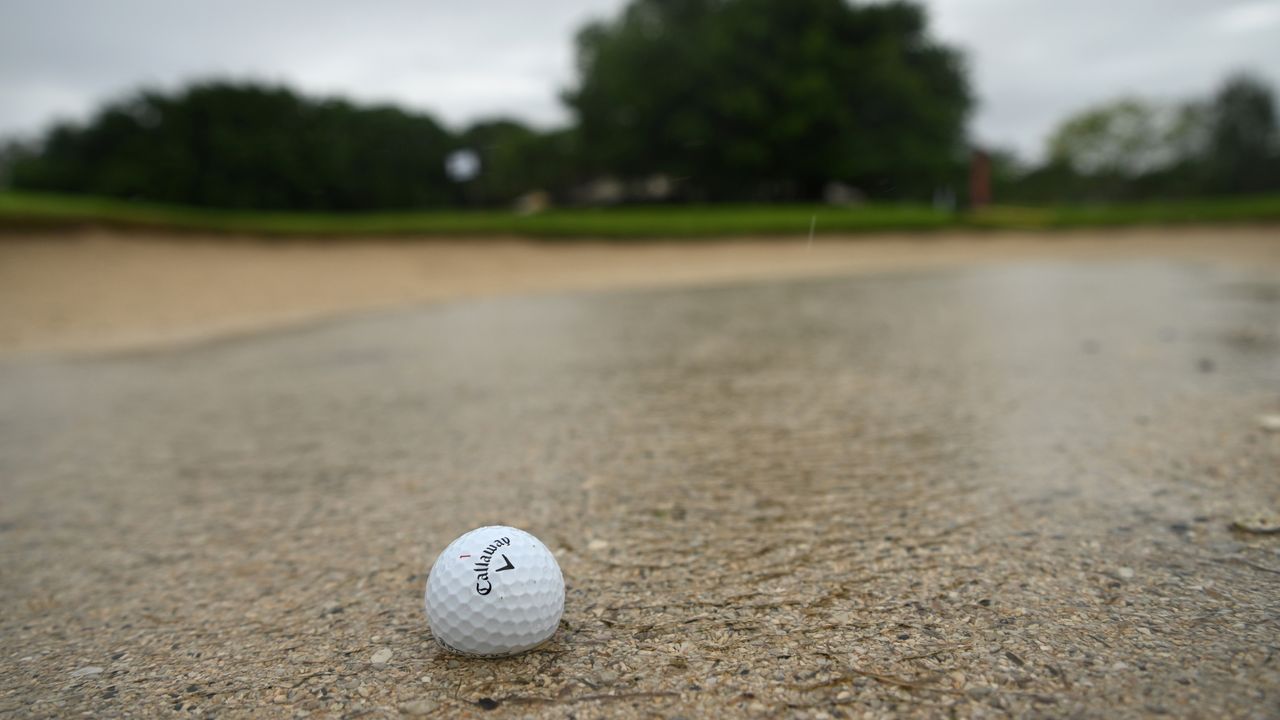 Golf ball in a puddle in a bunker