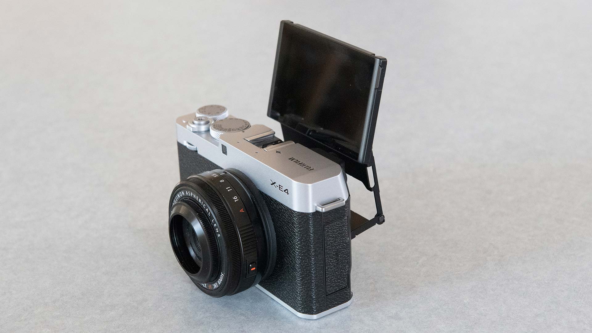 The Fujifilm X-E4 camera showing the front and side, with the rear screen flipped out