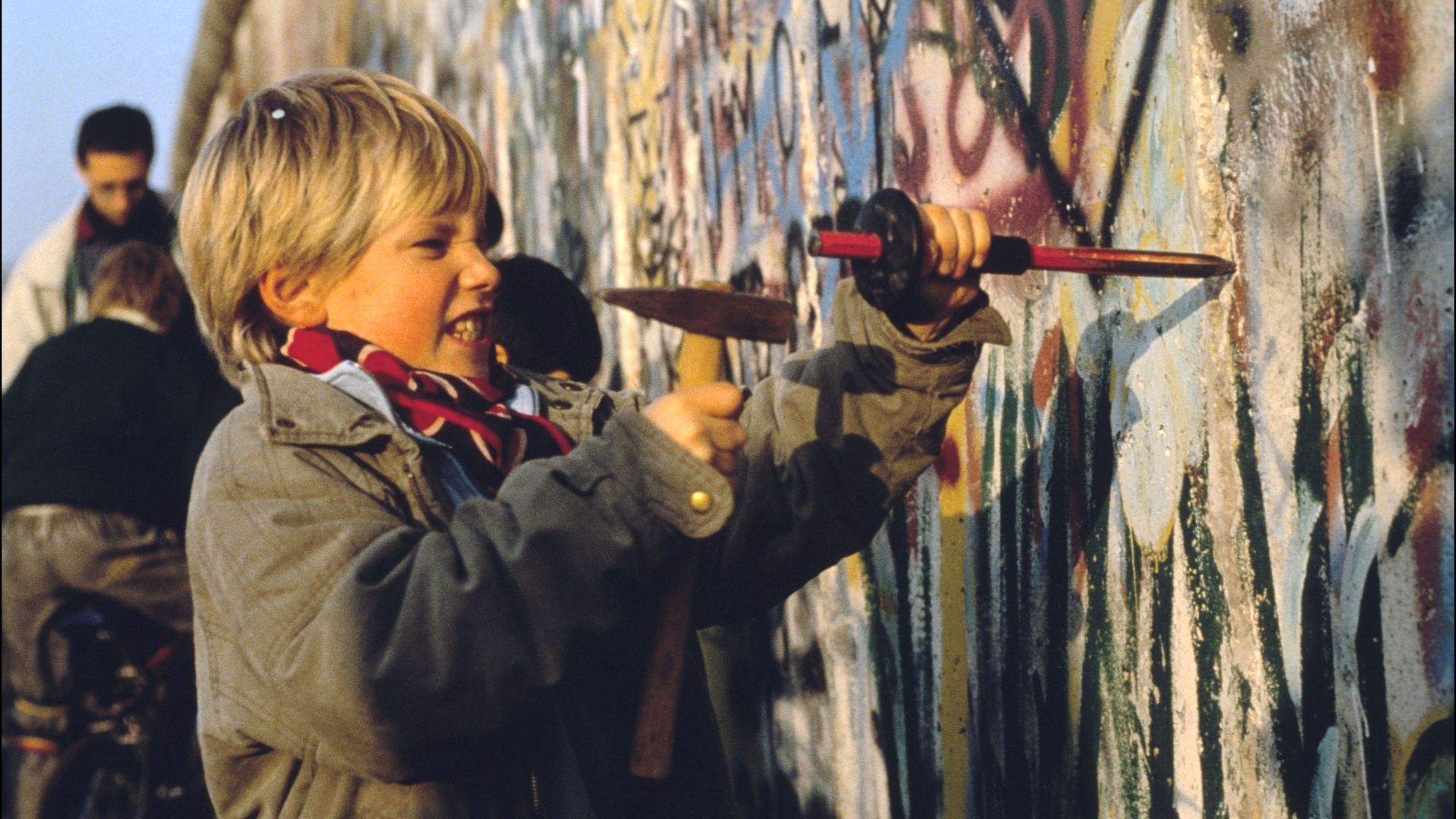 A young child chips away at the Berlin Wall