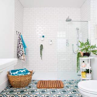 Bathroom with large white shower cubicle, white wall tiles and patterned floor tiles and wall hooks